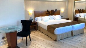 A hotel room with a large bed, a desk with a chair, a bedside table, and a mirror. - Hotel Olid (Valladolid)