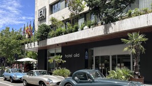 A hotel named "hotel old" with a modern facade, parked vintage cars, and flags. - Hotel Olid (Valladolid)