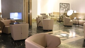 A modern lobby with a marble floor, multiple seating areas, a television, and a decorative partition. - Hotel Olid (Valladolid)