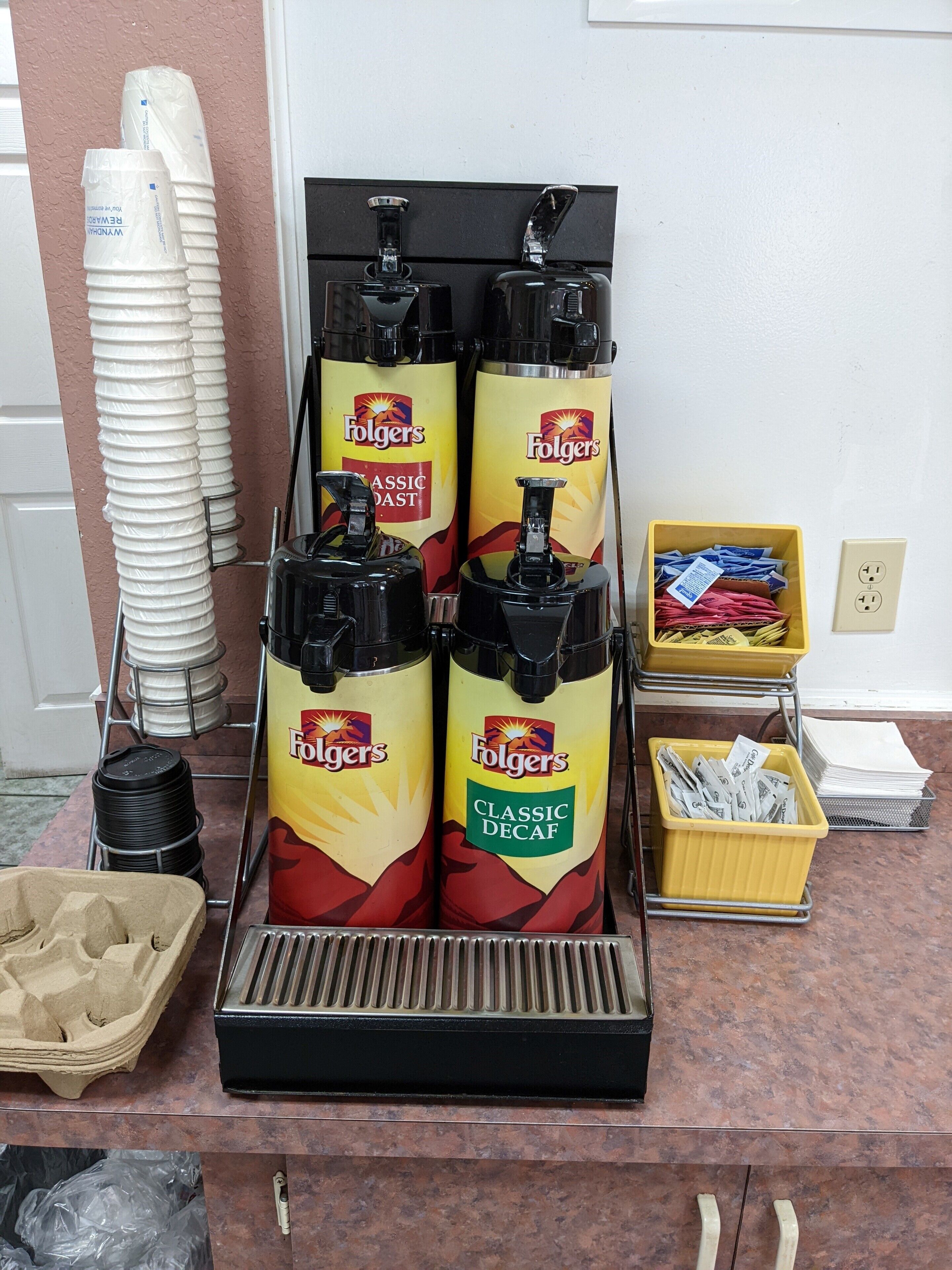 Dispensador de bebidas con dos columnas etiquetadas 'Folgers Classic Decaf' y 'Folgers Classic Roast'.