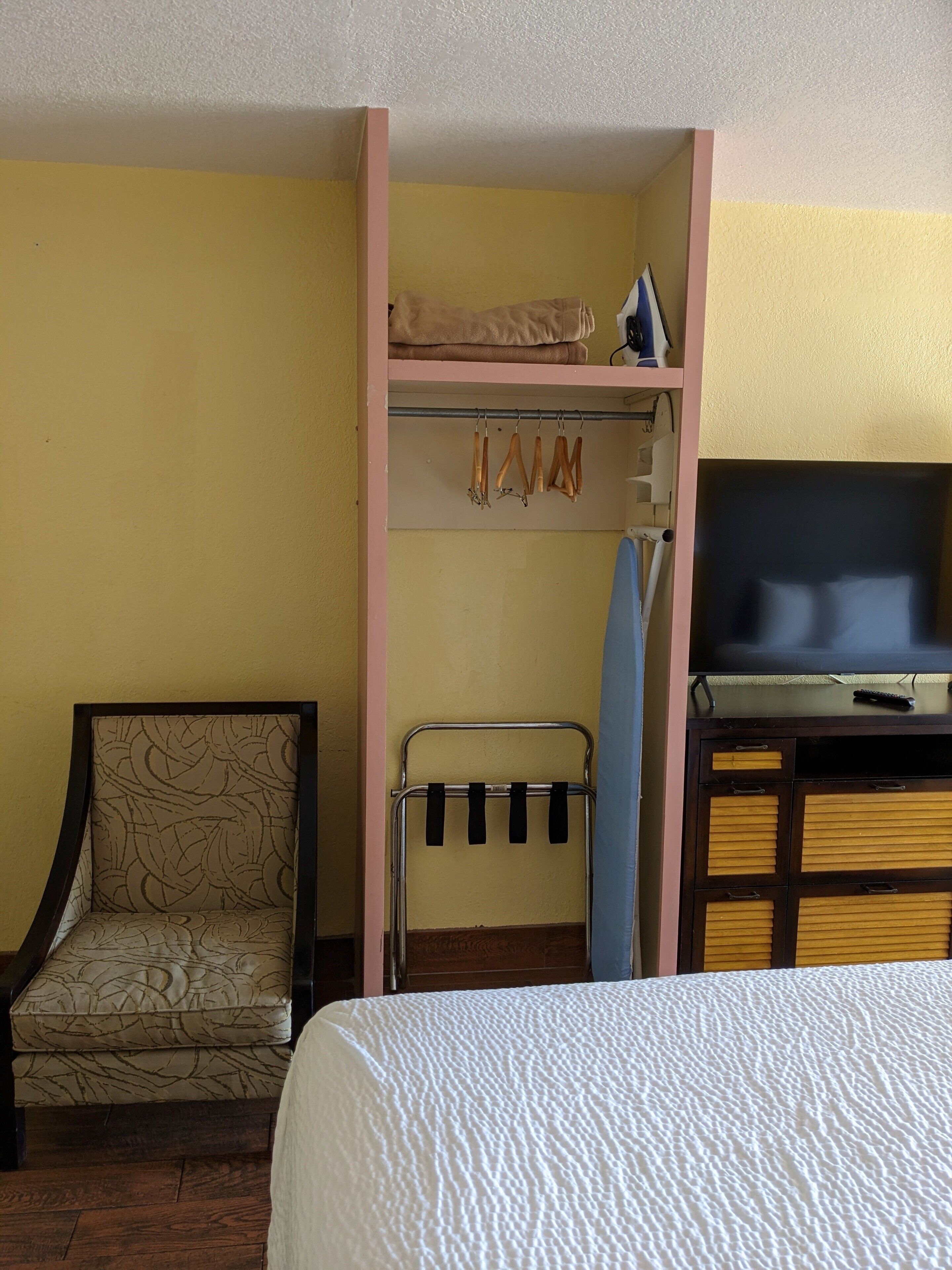 A room with a bunk bed, a chair, a TV, and a shelf with items.