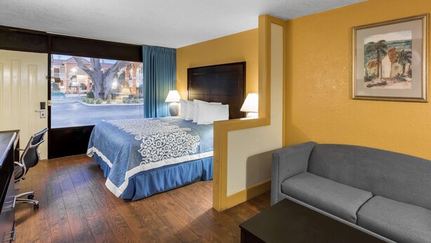 Une chambre d’hôtel avec un lit, un bureau, une chaise, un canapé et un tableau au mur.