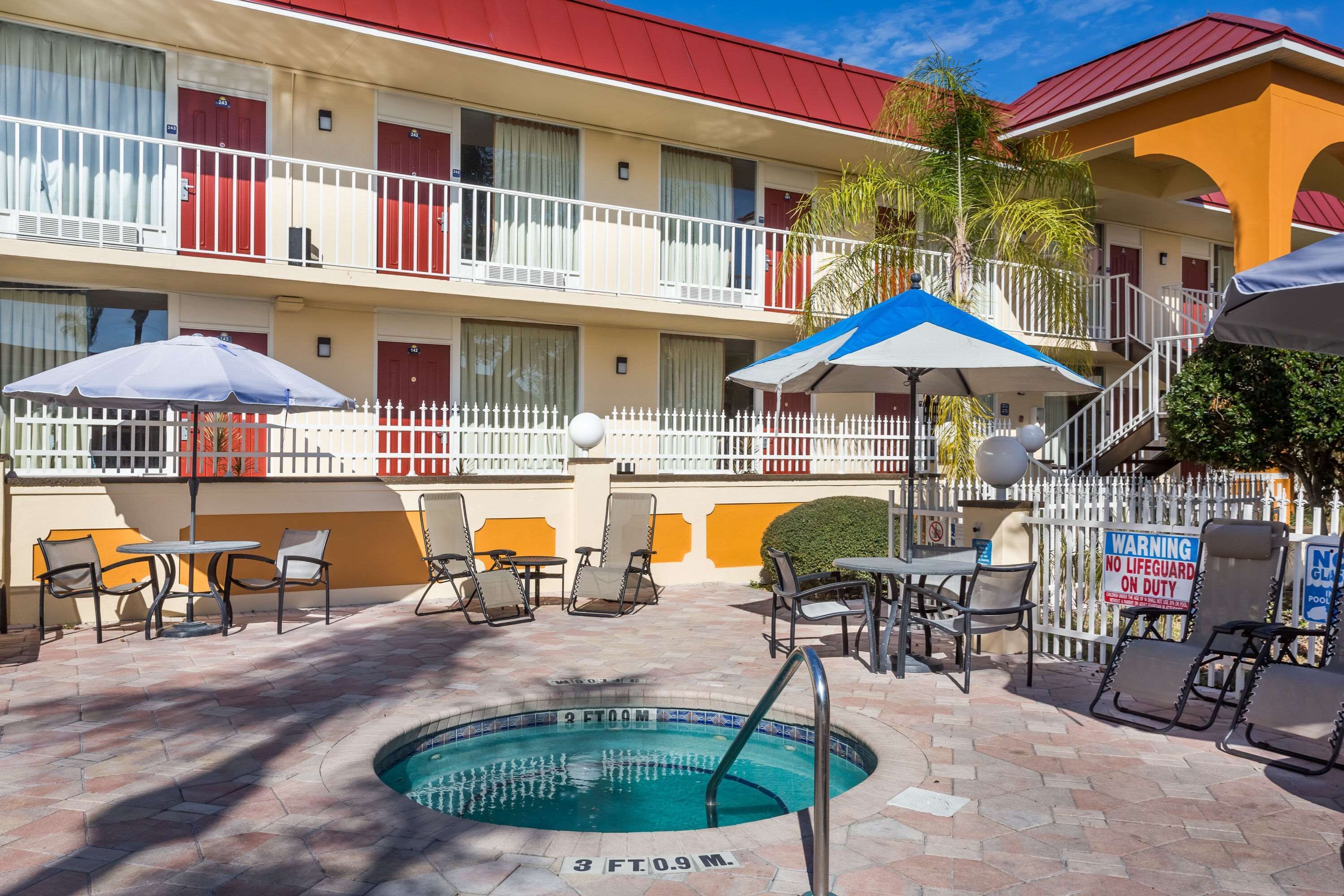 A hotel with a swimming pool, outdoor seating, and a red and yellow facade.