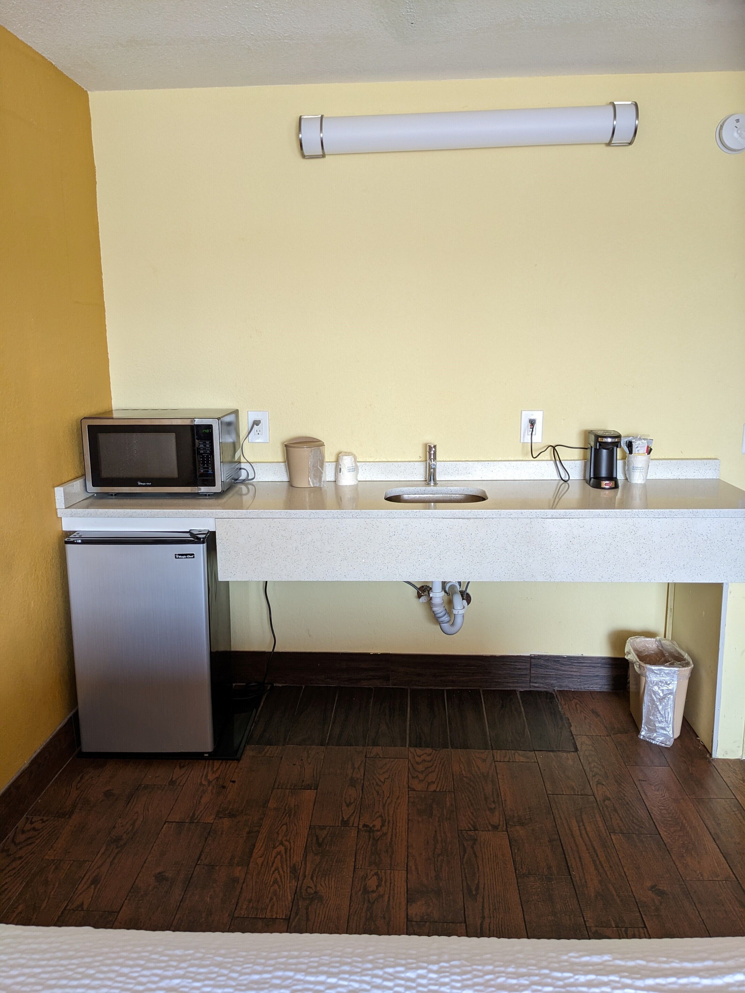 A compact kitchenette with a microwave, coffee maker, and small refrigerator.