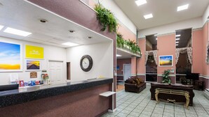 Un espace d’accueil d’hôtel comprenant un comptoir de réception, une horloge et un canapé.