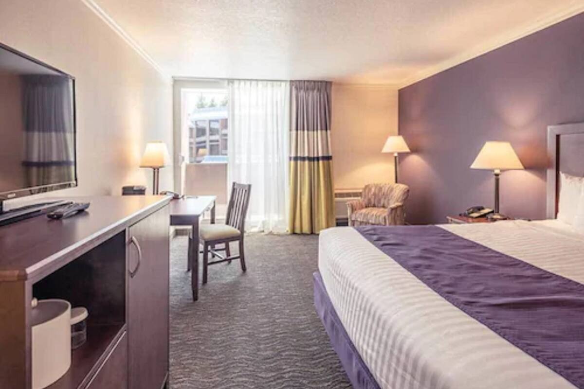 Une chambre d’hôtel comprenant un lit, un bureau, une chaise, une télévision et deux lampes.