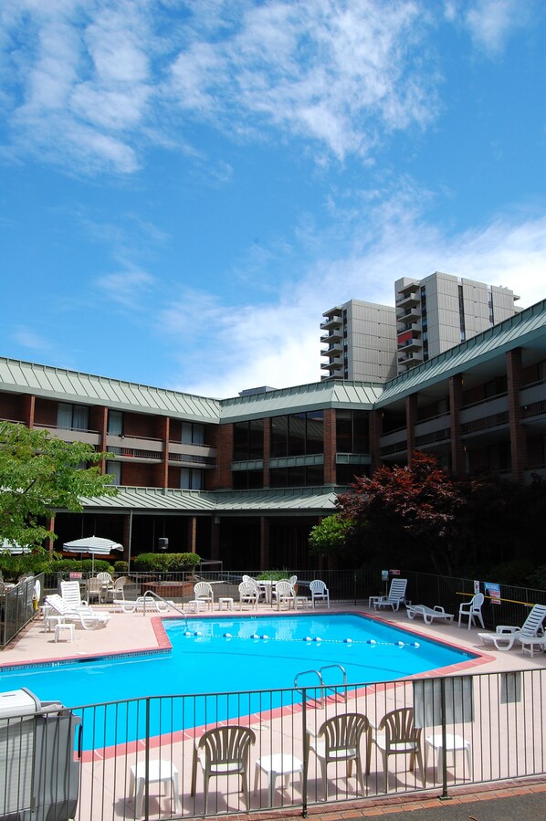 A swimming pool with lounge chairs and a building in the background.