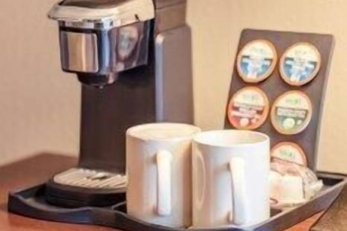 Une machine à café avec un plateau rempli de tasses et un assortiment de dosettes de café.