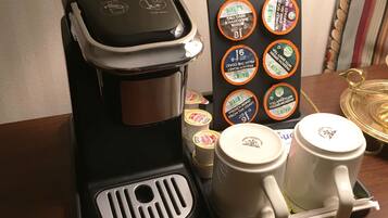 A coffee maker with a drip tray, a mug holder, and a coffee pod holder with various brands.