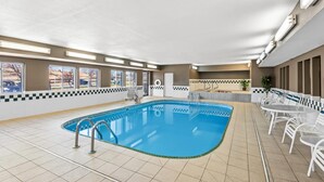 A swimming pool with a checkered border, a sunroof, and a seating area with white tables and chairs. - Quality Inn & Suites Des Moines Airport (Des Moines)