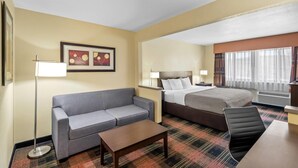 A hotel room with a bed, a sofa, a coffee table, and a desk. - Quality Inn & Suites Des Moines Airport (Des Moines)