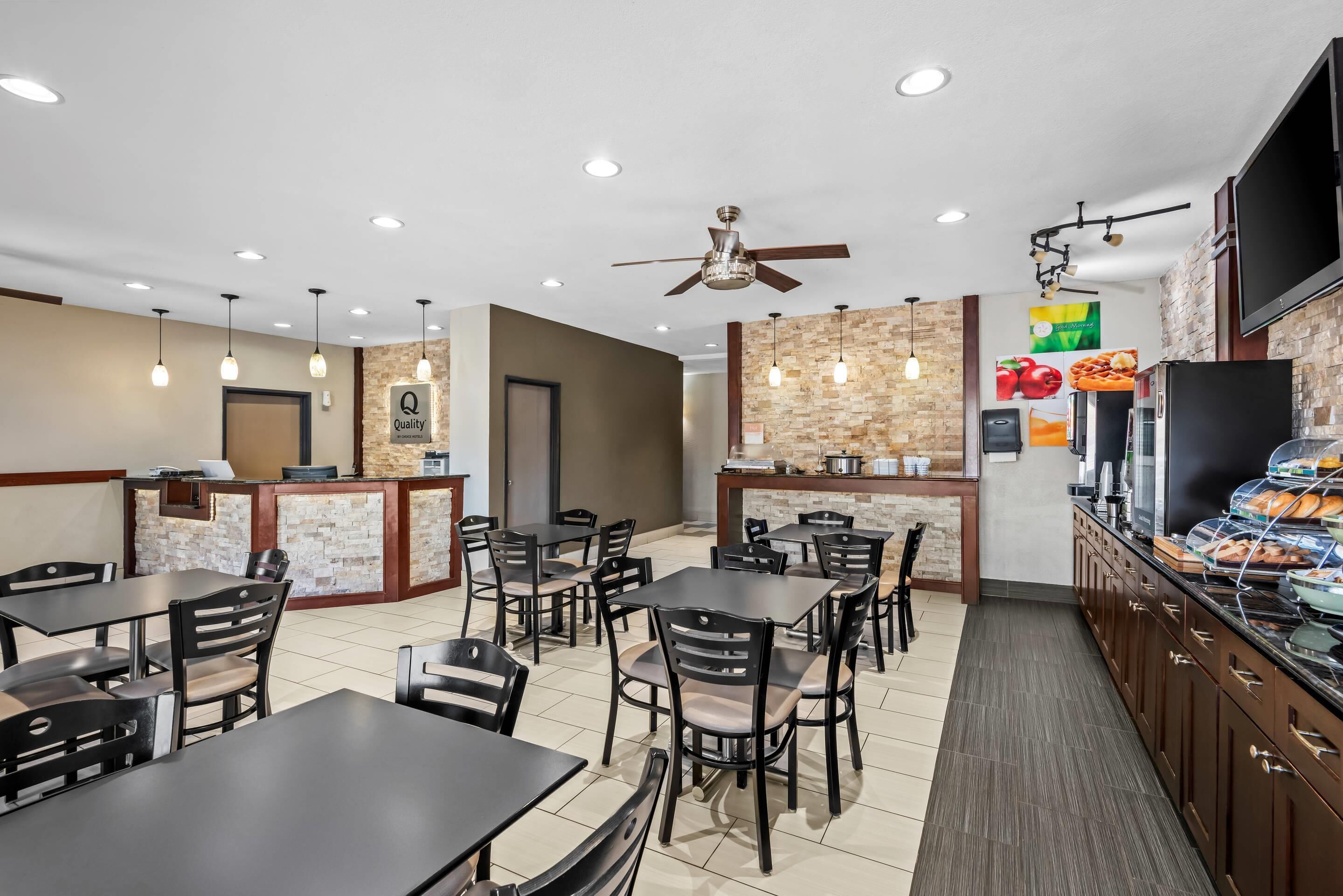 A restaurant with a counter, tables, chairs, and a buffet area.