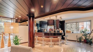 A modern bar area with a curved counter, stools, and a polished floor. - Garden Hotel Michelangelo (Mestre)