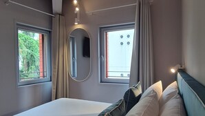 A bedroom with a large bed, two windows, a mirror, and a ceiling with exposed beams. - Garden Hotel Michelangelo (Mestre)