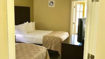 A hotel room with two beds, a desk, and a television.