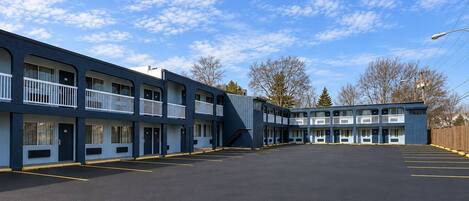 A motel with a two-story structure, a parking lot, and a clear sky.