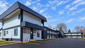 A motel with a two-story structure, a parking lot, and a clear sky.