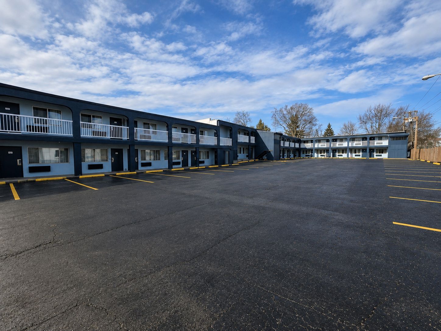 Ein Motel mit mehreren Zimmern, einem Parkplatz und blauem Himmel.