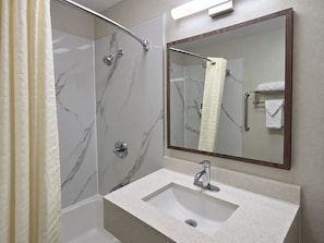 A bathroom with a shower, a sink, and a mirror.