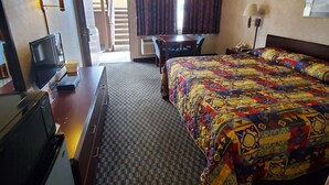 Ein Hotelzimmer mit Bett, Schreibtisch, Fernseher und einem Fenster mit Vorhängen.