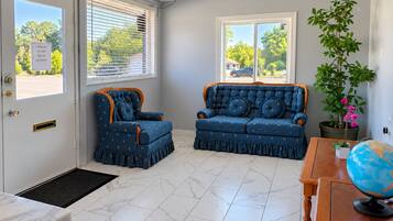 A room with a blue sofa set, a wooden side table with a globe, and a potted plant.