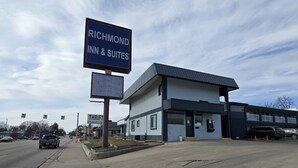 Ein Gebäude mit einem Schild für Richmond Inn & Suites, einem Parkplatz und einem Schild für kostenloses Highspeed-Internet und Satellitenfernsehen.