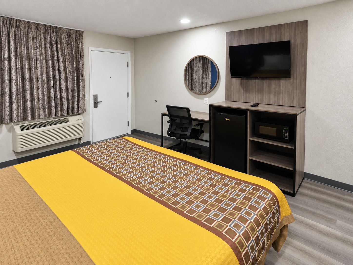 A hotel room with a bed, a desk, a television, and a minibar.
