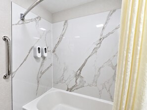 A bathroom with a shower, a toilet, and a hand dryer. - Richmond Inn & Suites Near Dayton I-70 (Richmond)