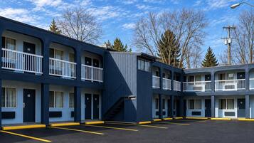 A motel with multiple floors, a parking lot, and a clear sky.