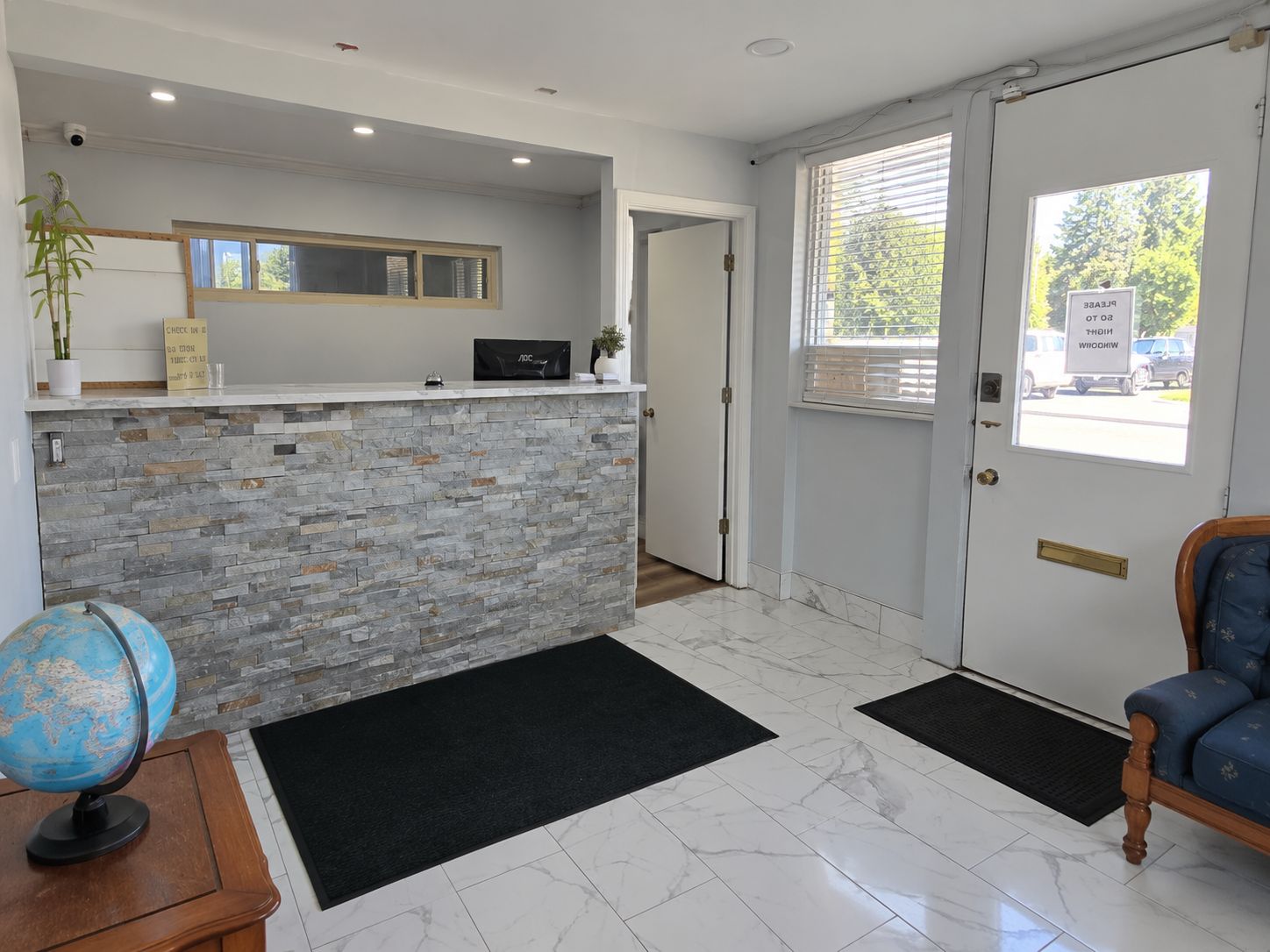 A reception area with a stone counter, a globe, a wooden desk, and a door leading outside.