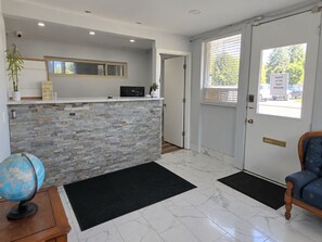 A reception area with a stone counter, a globe, a wooden desk, and a door leading outside. - Richmond Inn & Suites Near Dayton I-70 (Richmond)