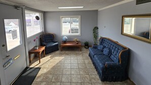 Ein Zimmer mit geschlossener Tür, zwei Fenstern, einem blauen Sofa, einem Holztisch, einem Globus und einem Spiegel.