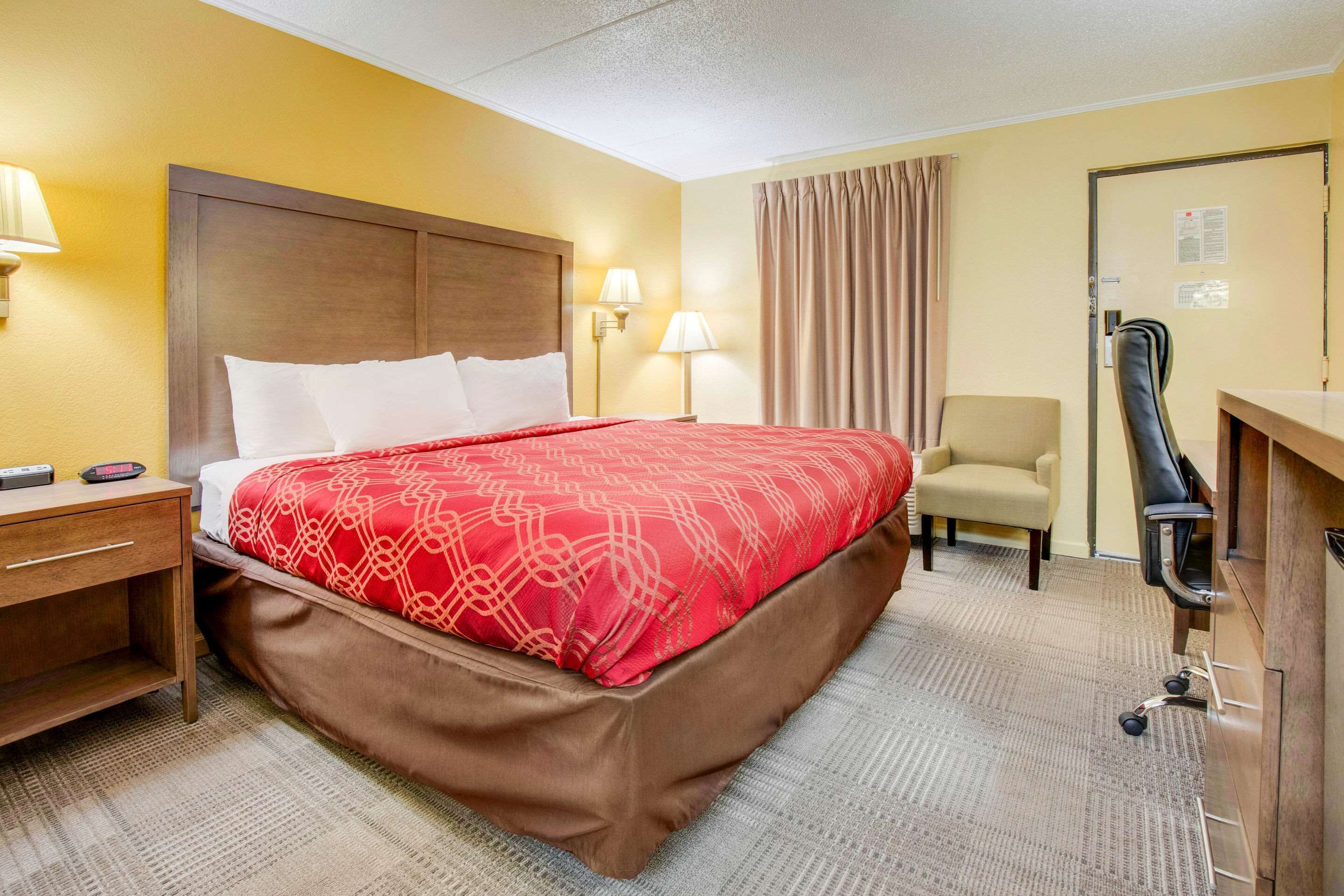 Une chambre d’hôtel avec un lit, un bureau, une chaise et une lampe de bureau.