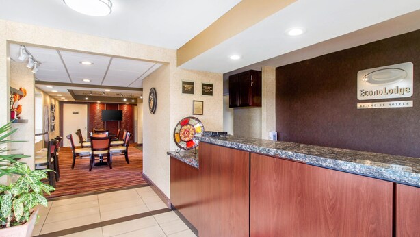 A hotel reception area with a wooden reception desk, a clock, and a sign for EconoLodge by Choice Hotels. - Econo Lodge Lenoir City - Knoxville Area (Lenoir City)