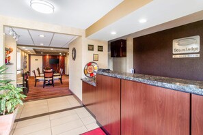 A hotel reception area with a wooden reception desk, a clock, and a sign for EconoLodge by Choice Hotels.