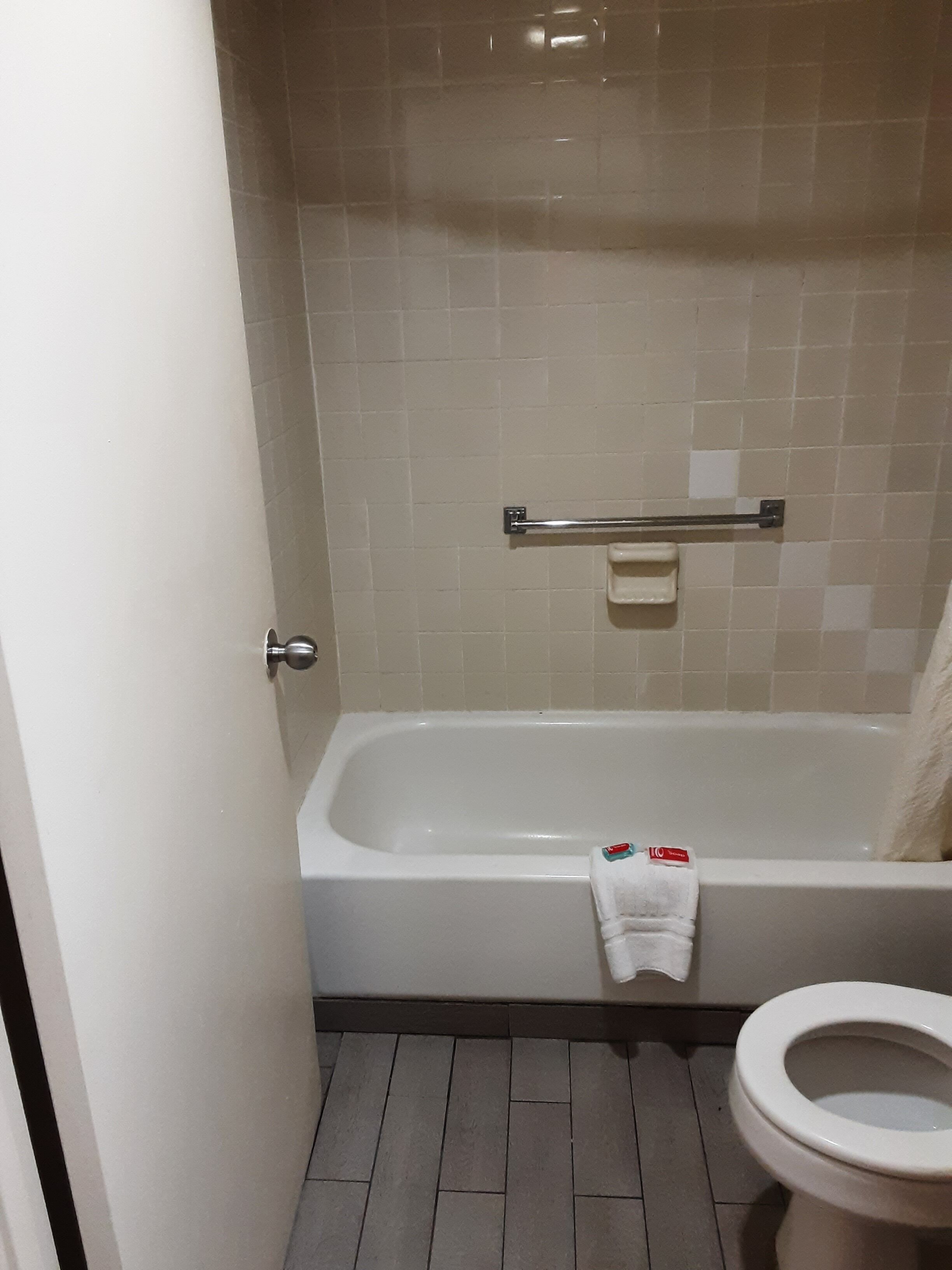Un baño con bañera, inodoro y barra para toallas.
