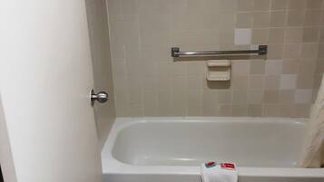 Un baño con bañera, inodoro y barra para toallas.