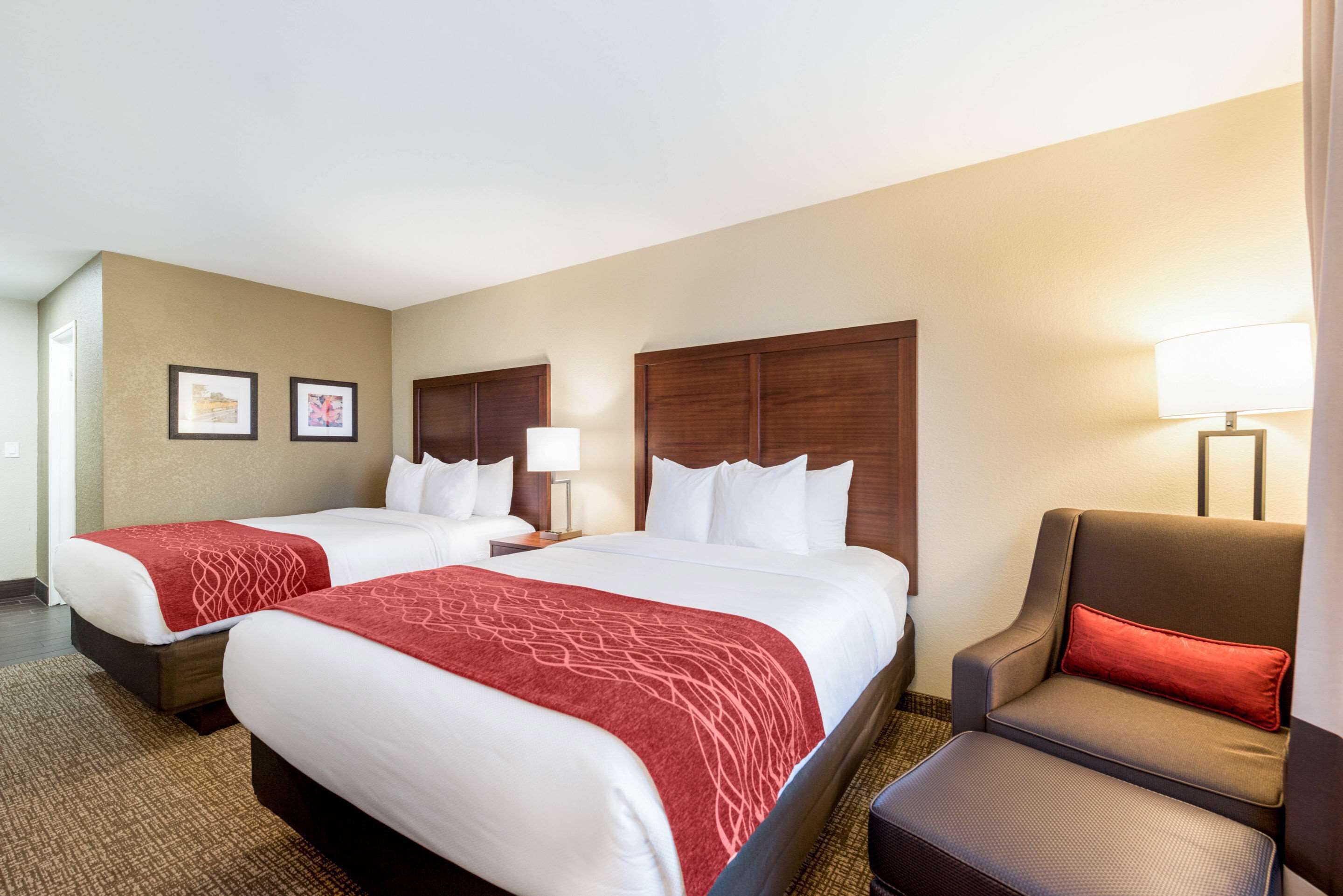 Habitación de hotel con dos camas, una silla y una lámpara.