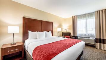 A hotel room with a large bed, two bedside tables with lamps, a chair, and a window with curtains.