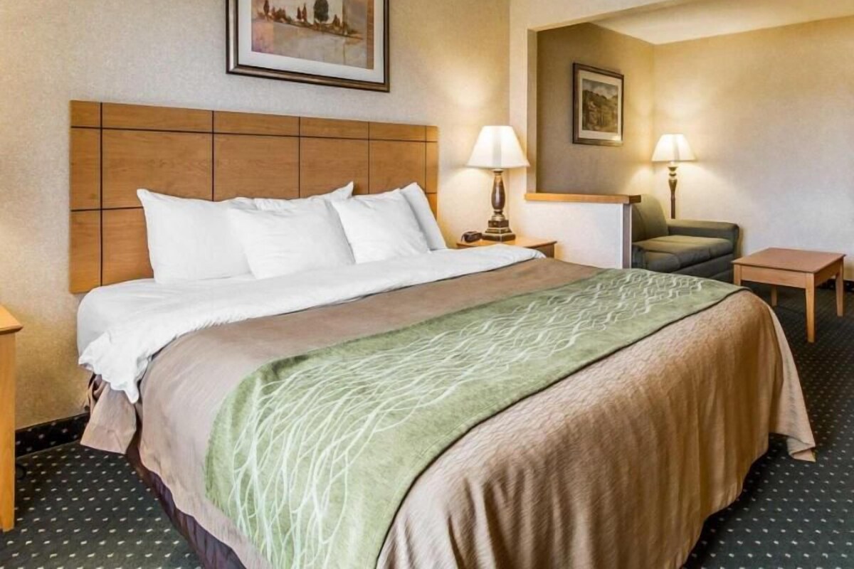 A hotel room with a bed, two bedside tables, a chair, and two wall-mounted lamps.