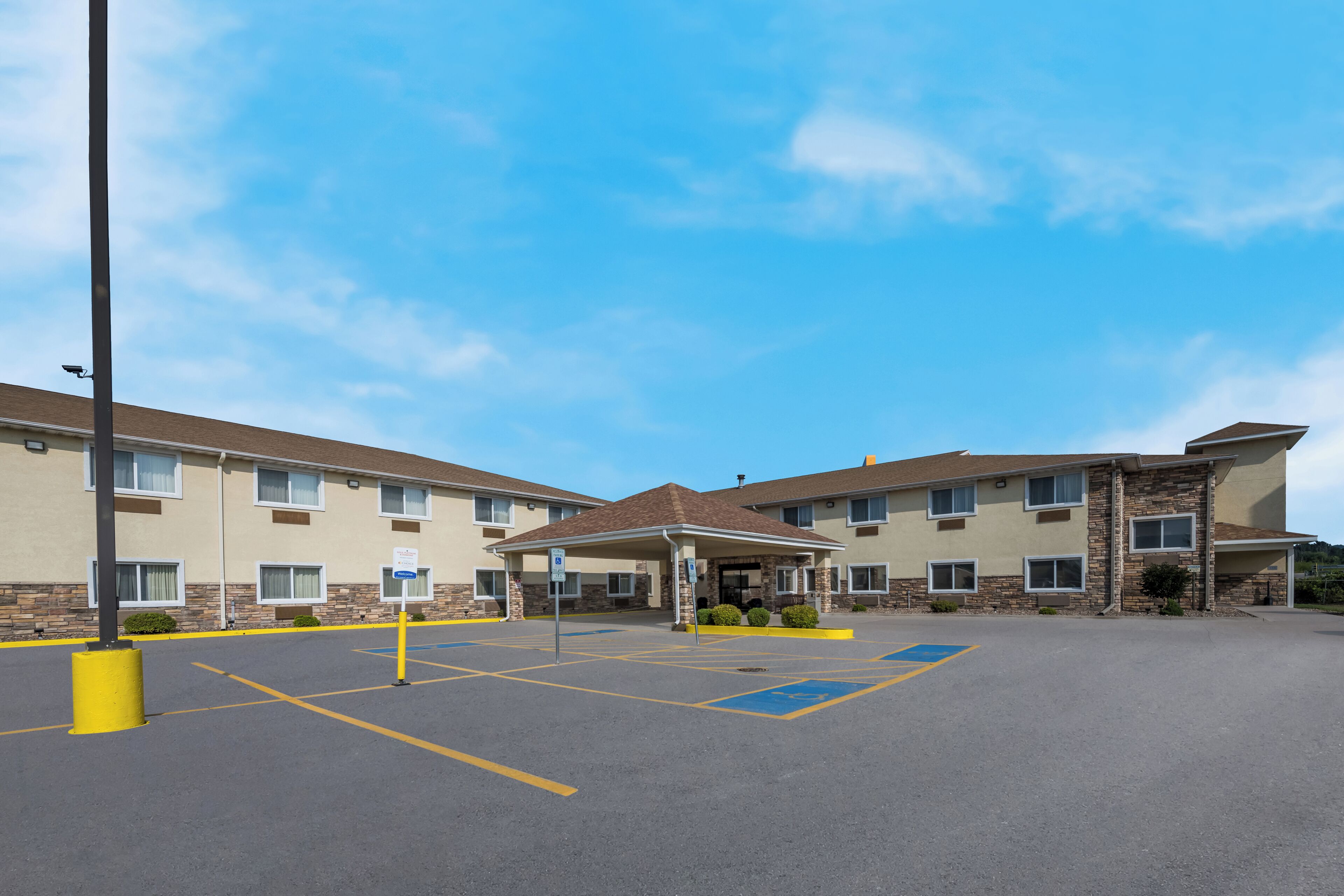 A two-story hotel with a covered entrance and a parking lot.