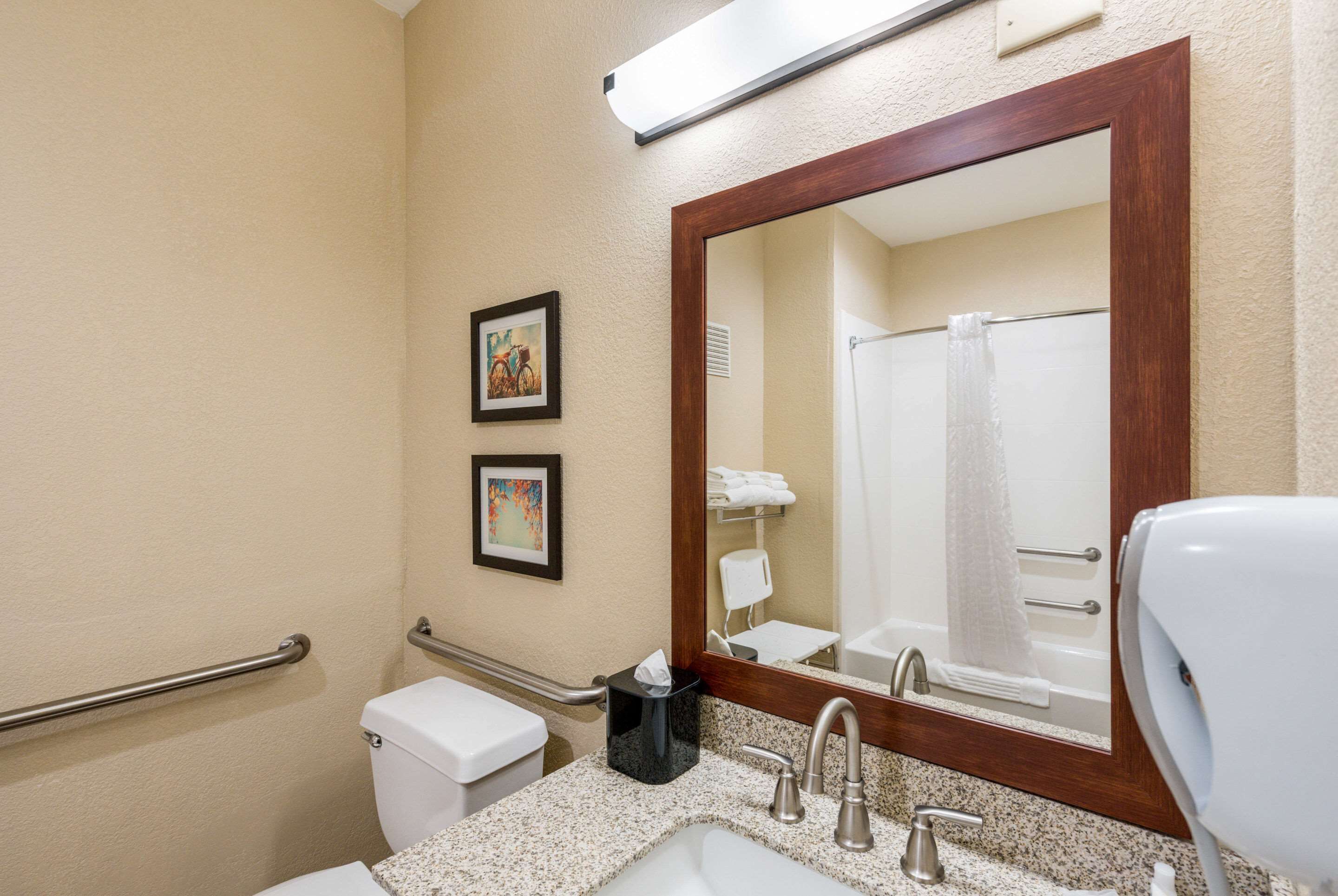Baño con lavamanos, espejo, toallero y secamanos.