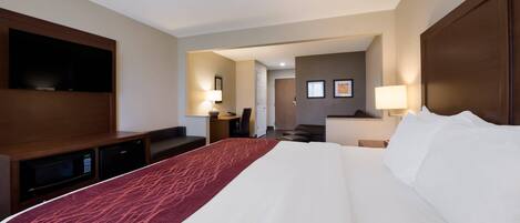 Une chambre d’hôtel dotée d’un grand lit, d’un téléviseur à écran plat fixé au mur, d’un bureau avec une lampe et d’un petit coin cuisine.