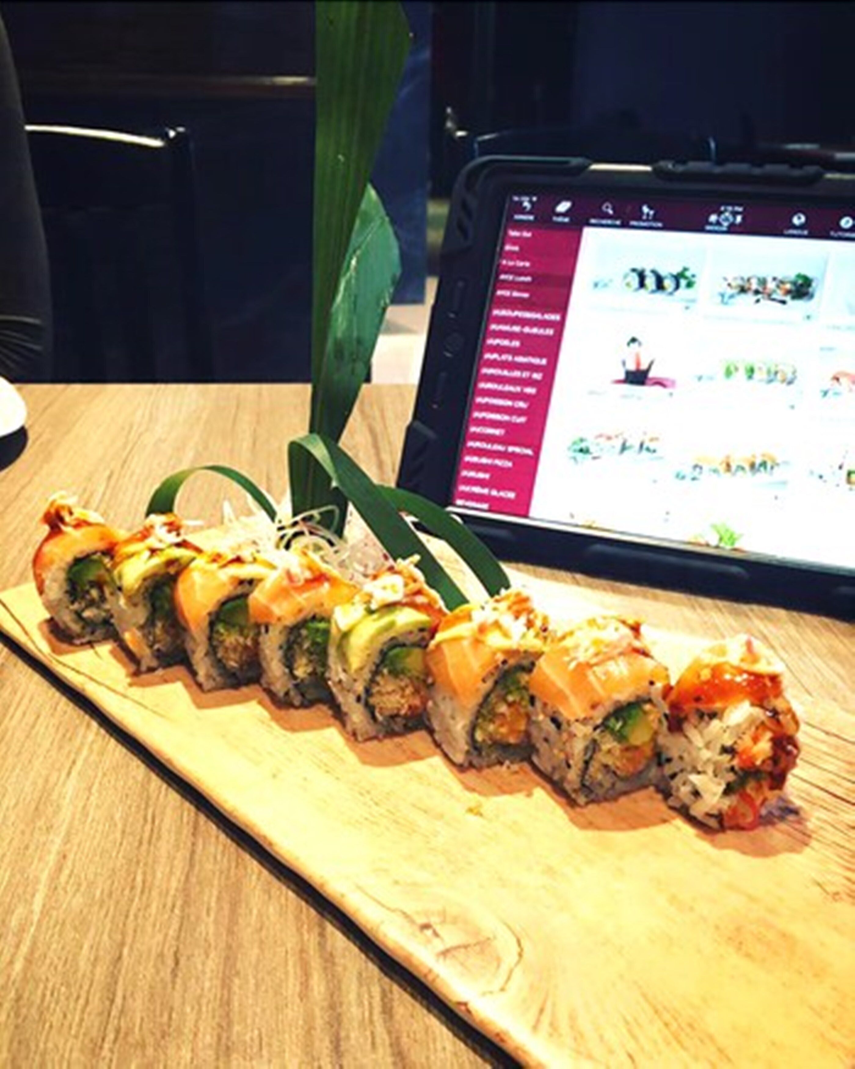 A wooden sushi platter with various rolls on a table.