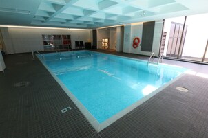 Una piscina interior con agua azul cristalina, paredes y suelo de azulejos.