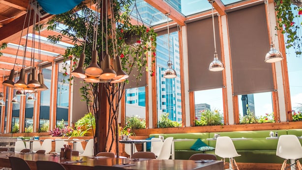A restaurant with wooden beams, hanging plants, and large windows offering city views. - Hotel Classique (Québec City)