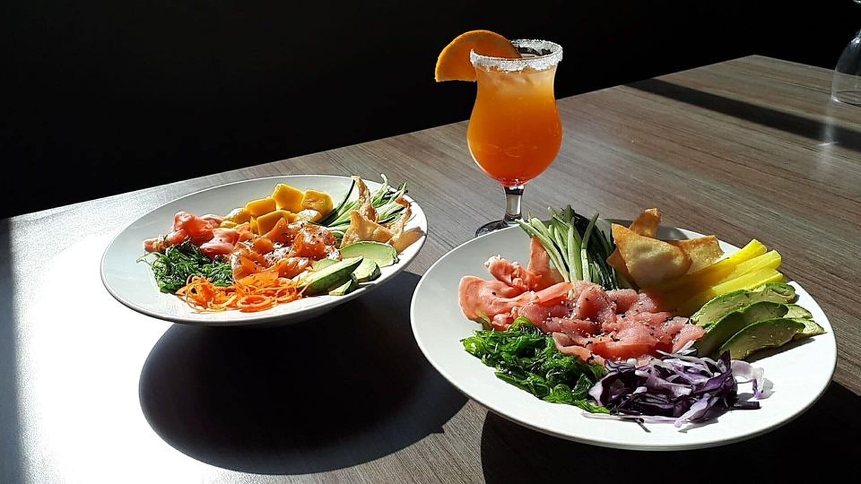 Dos platos de comida con una bebida sobre una mesa.