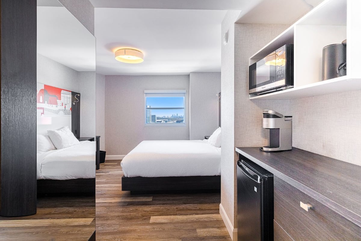 A hotel room with two beds, a city view, a microwave, and a built-in TV.