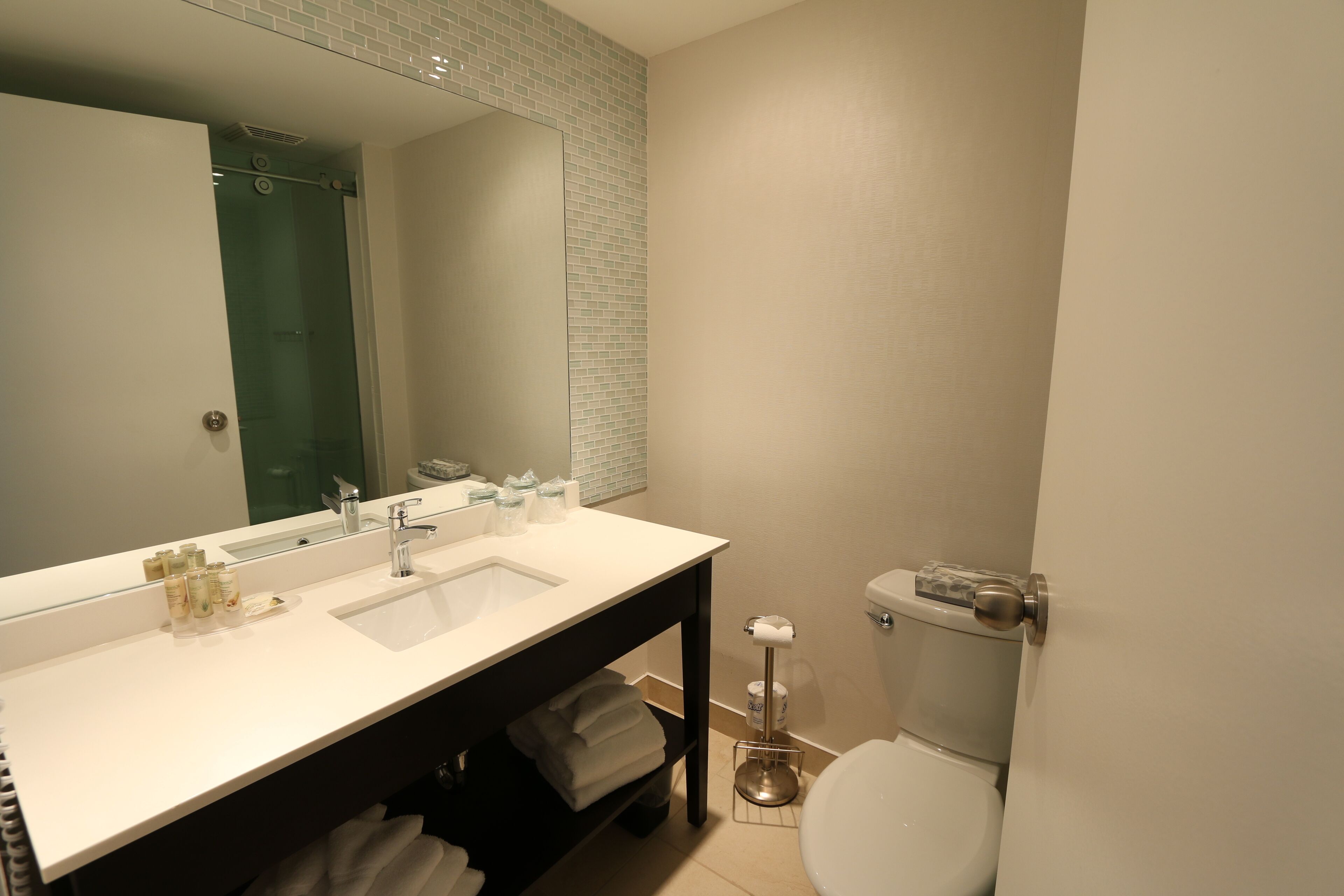 Un baño moderno con un espejo grande, lavamanos dobles y un inodoro.