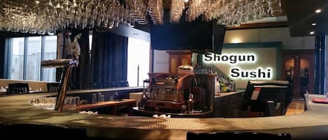 Ein Restaurantinneres mit einer Sushi-Bar, hängendem Glas und einem Vintage-Jukebox.
